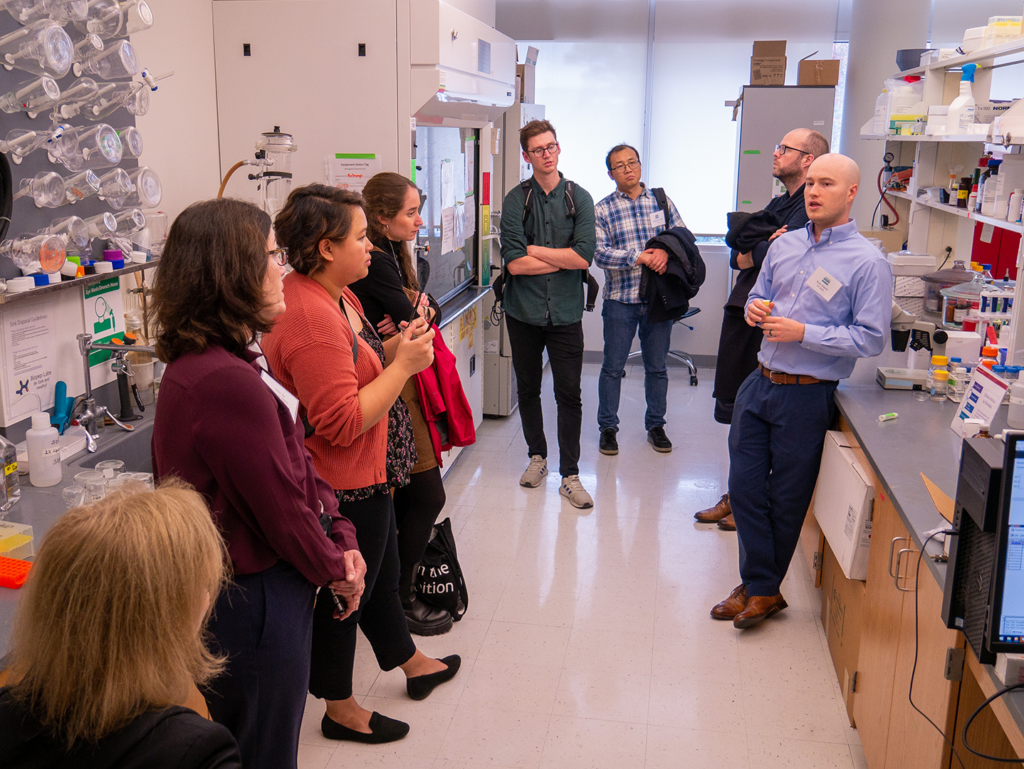 Ryan Kilgore, PhD student (far right), discusses AIM-Bio research in the Engineering Building 1 labs at NC State University.