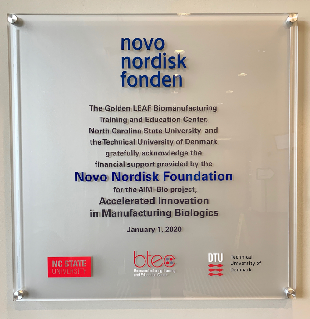 A plaque in the lobby of the Biomanufacturing Training and Education Center at NC State commemorates the AIM-Bio collaboration between NC State and DTU.